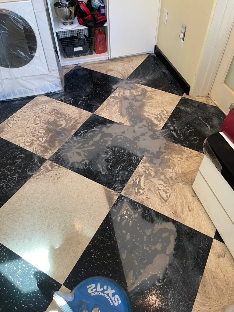 Mid-restoration process of stripping grime and old wax from checkerboard tile floors